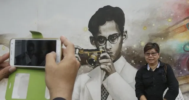 People take a picture of a drawing portrait of the late Thai King Bhumibol Adulyadej in Bangkok, Thailand, Tuesday, October 18, 2016. Bhumibol was 8 when he got hold of his first camera – a Coronet Midget given by his mother – and rarely was one out of reach through most of his life, capturing both domestic scenes and documenting his efforts to improve rural lives. (Photo by Sakchai Lalit/AP Photo)