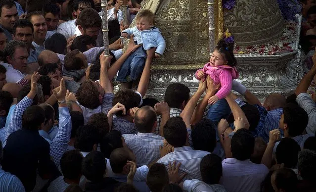 Children are carried by pilgrims to touch the Virgin of El Rocio in the village El Rocio, on May 20, 2013. (Photo by Miguel Angel Morenatti/Associated Press)