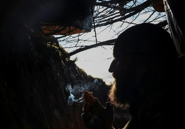 A Ukrainian service member from a 3rd separate assault brigade of the Armed Forces of Ukraine, smokes in a shelter at a front line, amid Russia's attack on Ukraine, near the city of Bakhmut, Ukraine on April 23, 2023. (Photo by Sofiia Gatilova/Reuters)