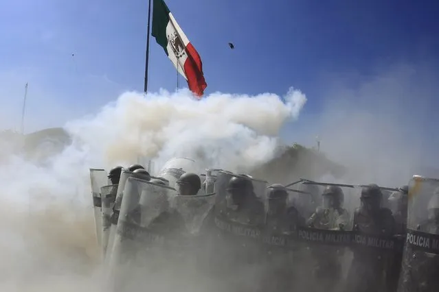Military police officers are seen amid smoke during a demonstration by activists and relatives of the 43 missing trainee teachers from Ayotzinapa's teacher training college, at the military zone of the 27th infantry battalion in Iguala, Guerrero, January 12, 2015. (Photo by Jorge Dan Lopez/Reuters)
