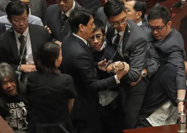 Newly elected Hong Kong lawmaker Sixtus Leung, center with glasses, is blocked by security guards wearing gray suits, as he tries to retake oath at legislature council in Hong Kong, Wednesday, November 2, 2016. Two newly elected pro-democracy Hong Kong lawmakers barred for insulting China in their swearing-in ceremony have set off another round of disorder by scuffling with guards as they tried to retake their oaths in the chamber. (Photo by Vincent Yu/AP Photo)