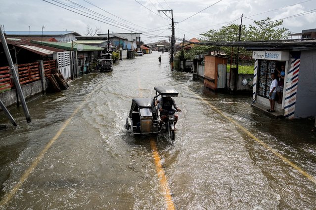 People ride a motorbike with a sidecar as it wades through a flooded road following flooding brought by high tide and Super Typhoon Fung-wong, in Macabebe town, Pampanga province, Philippines, on November 10, 2025. (Photo by Lisa Marie David/Reuters)