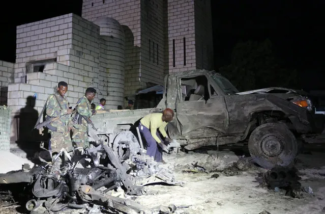 Somali soldiers and policemen inspect the scene of a suicide car explosion near the parliament in the capital Mogadishu, November 5, 2016. (Photo by Feisal Omar/Reuters)