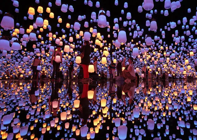In this Thursday, June 21, 2018, file photo, visitors walk through the installation of “Forest of Resonating Lamps” at the Mori Building Digital Art Museum in Tokyo, Thursday, June 21, 2018. Mori Building, a Japanese real estate company and teamLab, digital art collective company, have joined together to create the digital art museum in Tokyo. “MORI Building DIGITAL ART MUSEUM: teamLab Borderless'” exhibition displayed 50 interactive artworks in a 10,000 square-meter space. (Photo by Shuji Kajiyama/AP Photo)