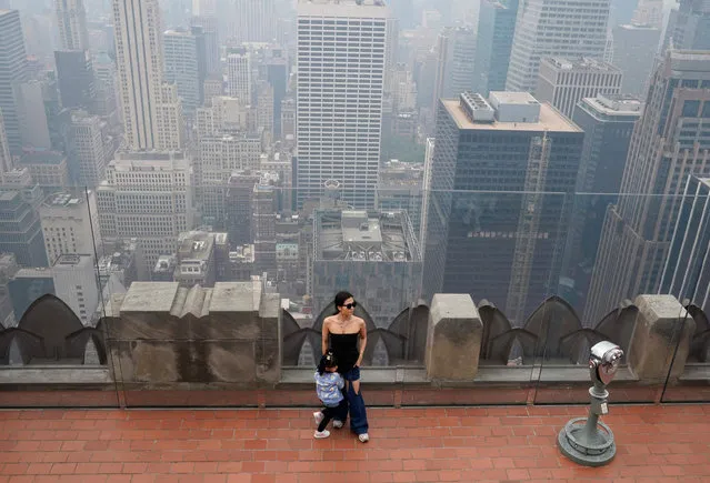 A person looks out at Midtown Manhattan in the haze from the Top of the Rock NYC Observation Deck at Rockefeller Center on June 7, 2023. Smoke from Canada’s wildfires has engulfed the Northeast and Mid-Atlantic regions of the US, raising concerns over the harms of persistent poor air quality. (Photo by Timothy A. Clary/AFP Photo)