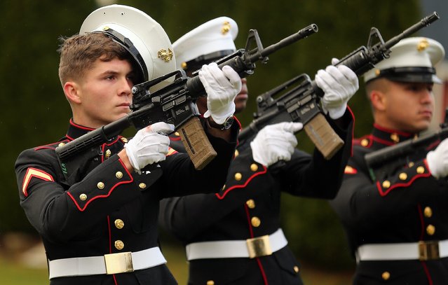 The gusty winds blow off the cap of of one of the members of the SWFPAC Marine Detachment as they perform a rifle volley during the Wreaths Across America ceremony at Ivy Green Cemetery in Bremerton, Wash. on Saturday, December 14, 2024. (Photo by USA Today)