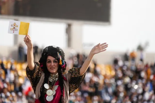 A woman waves a Vatican flag as she waits for Pope Francis to hold a mass at Franso Hariri Stadium in Erbil, Iraq, March 7, 2021. (Photo by Yara Nardi/Reuters)