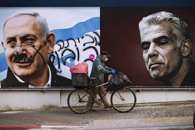 An election campaign billboard for the Likud party that shows a portrait of its leader Prime Minister Benjamin Netanyahu, left, and opposition party leader Yair Lapid, is defaced with Hebrew that reads, “go home”, in Ramat Gan, Israel, Sunday, March 21, 2021. Israelis head to the polls on Tuesday for what will be the fourth parliamentary election in just two years. Once again, the race boils down to a referendum on Prime Minister Benjamin Netanyahu. (Photo by Oded Balilty/AP Photo)