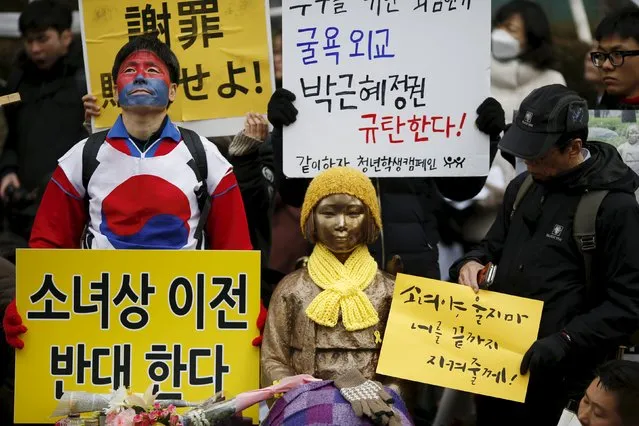 People hold placards next to a statue symbolizing “comfort women” during a weekly anti-Japan rally in front of Japanese embassy in Seoul, South Korea, December 30, 2015. The placard (bottom L) reads, “Oppose the relocation of the statue”. (Photo by Kim Hong-Ji/Reuters)