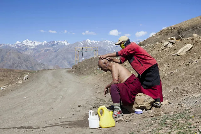 In this photograph taken on July 9, 2018, an Indian Buddhist monk shaves the head of another outside Tnagyud Gompa monastery in Komik in Spiti Valley in the northern state of Himachal Pradesh. (Photo by Xavier Galiana/AFP Photo)