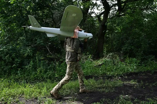 A Ukrainian serviceman of an air reconnaissance squad of the 45th Brigade carries a Leleka reconnaissance UAV after its landing at a position in Donetsk region on June 27, 2023, amid the Russian invasion of Ukraine. (Photo by Genya Savilov/AFP Photo)