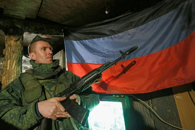 A militant of the self-proclaimed Donetsk People's Republic (DNR) holds a weapon at fighting positions on the line of separation from the Ukrainian armed forces south of the rebel-controlled city of Donetsk, Ukraine on April 2, 2021. (Photo by Alexander Ermochenko/Reuters)