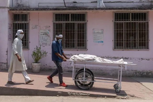 A man wheels the body of his relative who died from the coronavirus disease (COVID-19) outside a government-run hospital, amidst the coronavirus disease (COVID-19) pandemic, in Bijnor district, Uttar Pradesh, India, May 11, 2021. (Photo by Danish Siddiqui/Reuters)