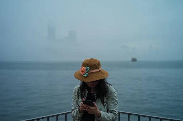 A woman stands next to a Victoria Harbour shrouded in fog in Lei Yu Mun in Hong Kong, China, 04 March 2018. In March the weather in Hong Kong is usually foggy as the humidity as the temperature go up. (Photo by Jerome Favre/EPA/EFE)