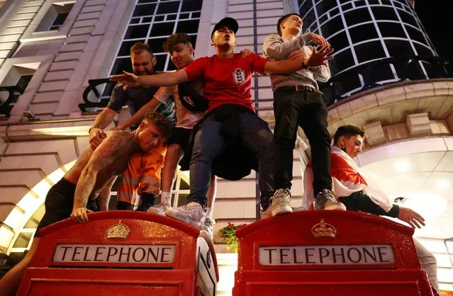 A group of lads climbed on top of telephone boxes in Piccadilly Circus in London, United Kingdom on July 7, 2021. (Photo by Henry Nicholls/Reuters)