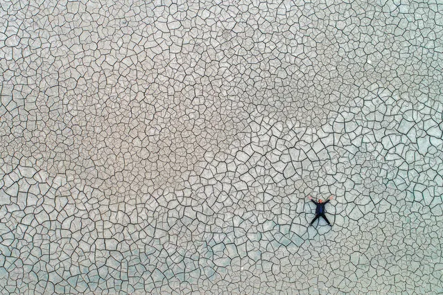 An aerial view of a man lying on the cracked soil ground of Lake Van, largest lake in Turkey, after a fall in water levels due to seasonal conditions in Enginsu neighbourhood in Edremit district of Turkey's eastern Van province on October 08, 2018. Water level at Lake Van lowered by 150 meters, revealing two sunken fishing boats. (Photo by Ozkan Bilgin/Anadolu Agency/Getty Images)
