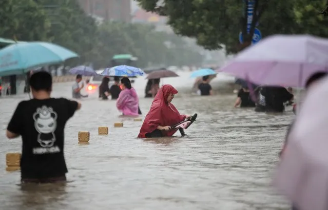 Residents wade through floodwaters on a flooded road amid heavy rainfall in Zhengzhou, Henan province, July 20, 2021. (Photo by China Daily via Reuters)