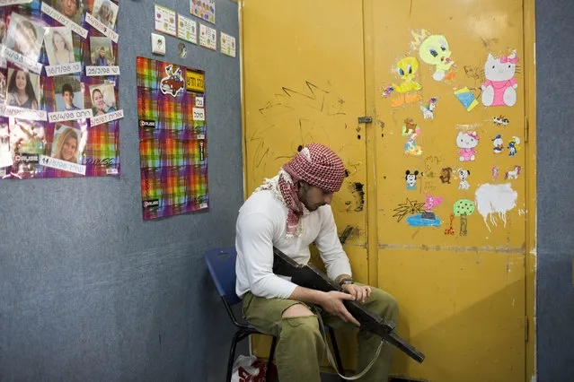In this Tuesday, March 24, 2015 photo, an Israeli high-school senior rests during urban fighting drill as part of a privately run military combat fitness training as part of privately run military combat fitness training to prepare for national military service in Kibbutz Mizra, northern Israel. (Photo by Oded Balilty/AP Photo)
