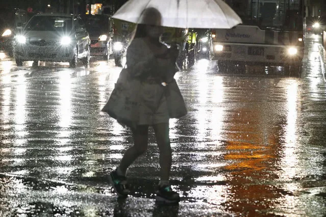 A woman holding umbrella makes her way through heavy rain in Fukuoka, western Japan, Thursday, August 12, 2021. Torrential rain pounding southwestern Japan has triggered a mudslide and swallowed four people in Nagasaki and threatened the region with the risk of floods and more landslides, officials said Friday. (Photo by Kyodo News via AP Photo)