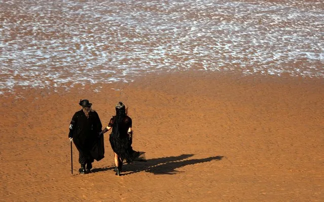 A couple walk on the beach during the Gothic Weekend in Whitby, Britain on October 28, 2022. (Photo by Lee Smith/Reuters)