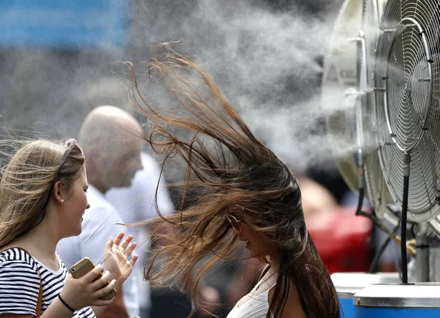 A spectator cools herself at a water spraying fan at the Australian Open tennis championships in Melbourne, Australia, Tuesday, January 17, 2017. (Photo by Kin Cheung/AP Photo)