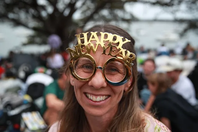 A woman poses for a photo wearing a Happy New Year headpiece at Mrs Macquarie's Chair during New Year's Eve celebrations on December 31, 2023 in Sydney, Australia. Revellers turned out in large numbers to celebrate the new year in Australia. (Photo by Roni Bintang/Getty Images)