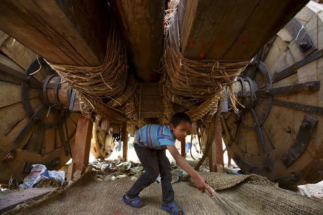A boy sweeps under the chariot of Rato Machhindranath during the chariot festival at Bungamati in Lalitpur April 22, 2015. (Photo by Navesh Chitrakar/Reuters)