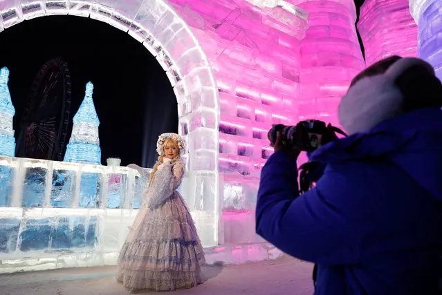 A woman dressed up in a costume poses for pictures in front of an ice sculpture depicting a castle, at the Harbin International Ice and Snow Festival, in Harbin, Heilongjiang province, China on January 4, 2024. (Photo by Tingshu Wang/Reuters)