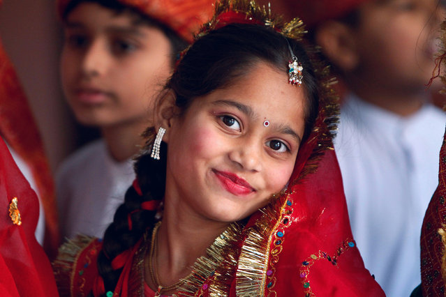 An Indian girl dressed in traditional attire reacts to camera as she watches a cultural performance during Lohri festival in Jammu, India, Monday, January 13, 2014. Lohri is a celebration of the winter solstice observed by Hindus and Sikhs in northern India. (Photo by Channi Anand/AP Photo)
