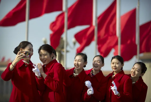 Bus ushers react as they pose for a selfie during a meeting one day ahead of the opening session of China's National People's Congress (NPC) at the Great Hall of the People in Beijing, Monday, March 4, 2019. A year since removing any legal barrier to remaining China's leader for life, Xi Jinping appears firmly in charge, despite a slowing economy, an ongoing trade war with the U.S. and rumbles of discontent over his concentration of power. (Photo by Mark Schiefelbein/AP Photo)