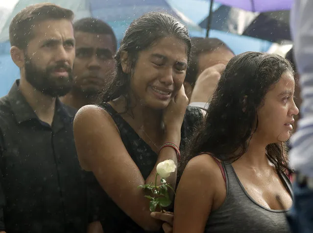A woman stands weeping in the rain during the burial of 15-year-old student Kaio Lucas da Costa Limeira, a victim of a mass shooting at the Raul Brasil State School in Suzano, Brazil, Thursday, March 14, 2019. Classmates, friends and families began saying goodbye on Thursday, with thousands attending a wake in the Sao Paulo suburb while authorities worked to understand what drove two former students to attack the school with a gun, crossbows and small axes. (Photo by Andre Penner/AP Photo)