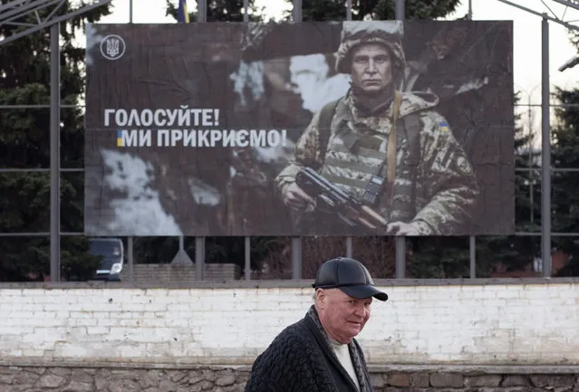 A local man walks past an election poster depicting a Ukrainian soldier with a sign reading “Go for vote, we protect you”, during the president elections in Mariinka, near a contact line not far from Donetsk, eastern Ukraine, Sunday, March 31, 2019. The exit poll released Sunday after voting stations closed indicated that Zelenskiy received about 30.4 percent of the nationwide vote, followed by incumbent President Petro Poroshenko with 17.8 percent and former Prime Minister Yulia Tymoshenko with 14.2 percent support. (Photo by Evgeniy Maloletka/AP Photo)