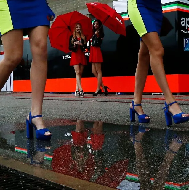 The reflection of two MotoGP umbrella girls in a rain puddle standing next to a riders garage while two others walk by during a weather delay for the MotoGP practice 3 at the Red Bull Grand Prix of the Americas at Circuit of the Americas in Austin, Texas, USA, 13 April 2019. (Photo by Larry W. Smith/EPA/EFE)