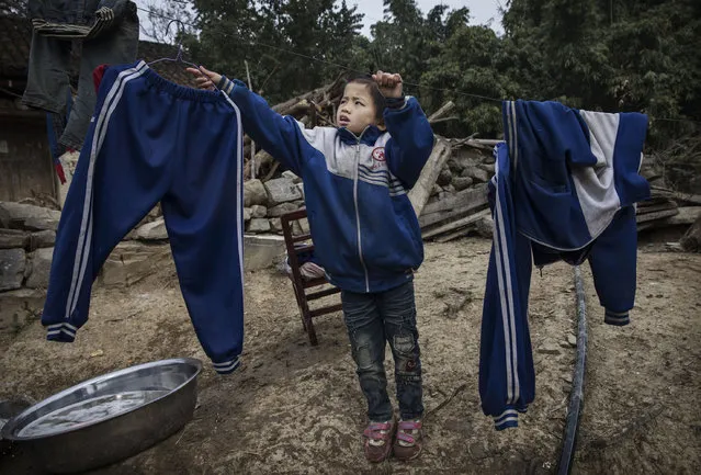 “Left behind” child Luo Hongniu, 8, hangs laundry after washing clothes with her siblings  on December 18, 2016 in Anshun, China. (Photo by Kevin Frayer/Getty Images)