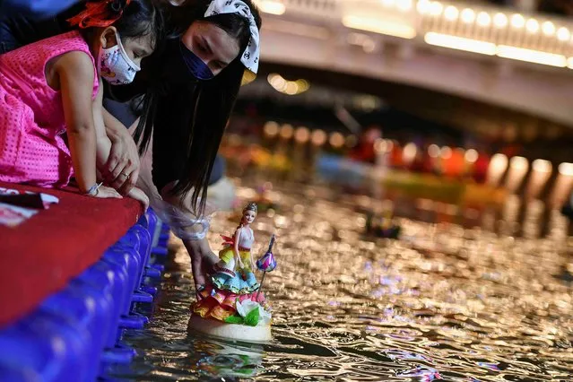 People wearing face masks to prevent the spread of the coronavirus disease (COVID-19), gather to place krathongs (floating baskets) into a river during the Loy Krathong festival, which is held as a symbolic apology to the goddess of the river in Bangkok, Thailand, November 19, 2021. (Photo by Chalinee Thirasupa/Reuters)