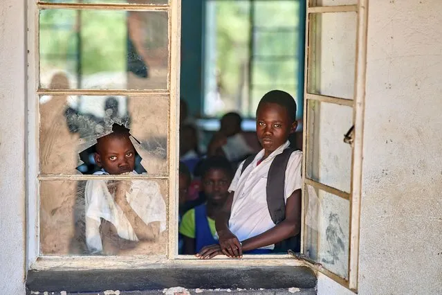 Learners look out from a school window at Mabale Primary near Hwange National Park in Hwange on March 7, 2023. International Foundation for Animal Welfare (IFAW) handed bicycles to support a riding for conservation and education initiative by providing bicycles to children who walk long distances of more than 5km to school in the elephant corridors. (Photo by Zinyange Auntony/AFP Photo)