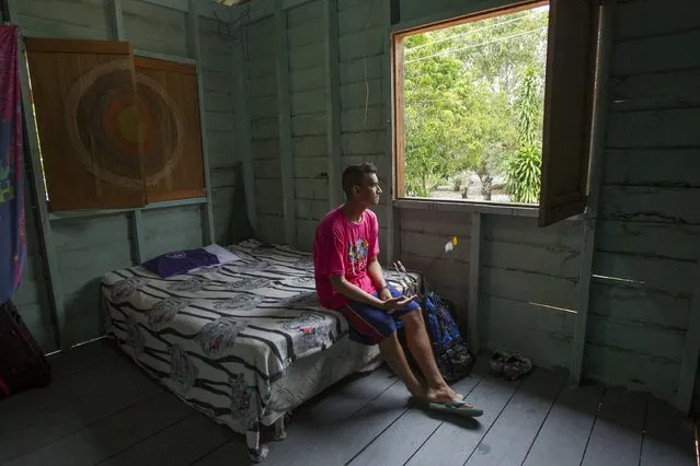 Kambeba Indian, Dream Braga, 18, looks out from his window at his home in the village Tres Unidos, Amazon state May 10, 2015. (Photo by Bruno Kelly/Reuters)