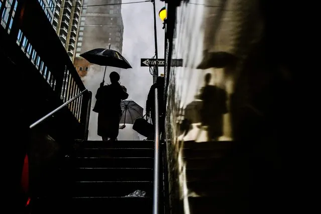 A person holding an umbrella enters a subway station under heavy rain in the Manhattan borough of New York on April 3, 2024. (Photo by Charly Triballeau/AFP Photo)