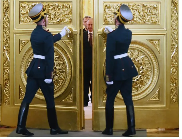 Honor guards open the doors for Russian President Vladimir Putin followed by Crimean leaders entering the hall for the signing ceremony of a treaty for Crimea to join Russia,  in the Kremlin in Moscow, Tuesday, March 18, 2014. President Vladimir Putin on Tuesday signed a treaty to incorporate Crimea into Russia, describing the move as the restoration of historic injustice and a necessary response to what he called the Western encroachment on Russia’s vital interests. (Photo by Sergei Ilnitsky/AP Photo)