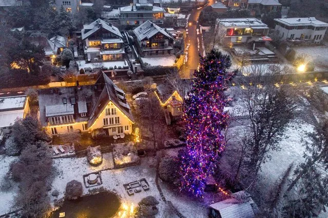 A giant Douglas fir is decorated with Christmas lights in a garden of a house in the small village of Falkenstein near Falkenstein, Germany, Friday, December 10, 2021. (Photo by Michael Probst/AP Photo)