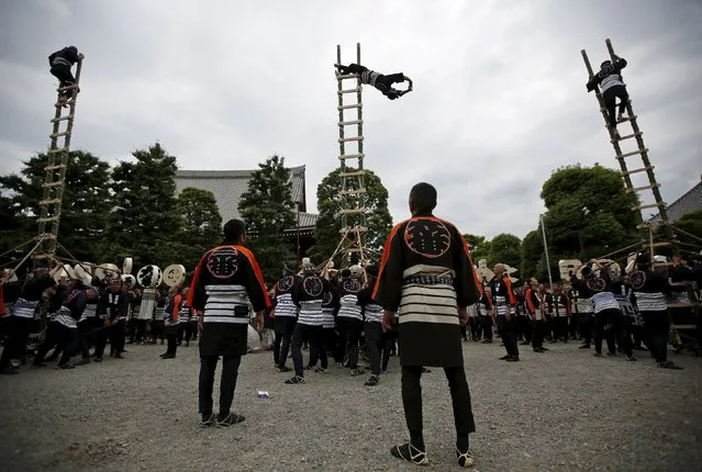 Men wearing costume of traditional firefighters perform acrobatic stunts atop a bamboo ladder following a memorial service for firefighters at Sensoji temple in Tokyo's downtown of Asakusa May 25, 2015. Hundreds of firefighters in traditional costume gathered on Monday for the memorial service for firefighters who were killed performing their duties during the past 300 years. (Photo by Issei Kato/Reuters)