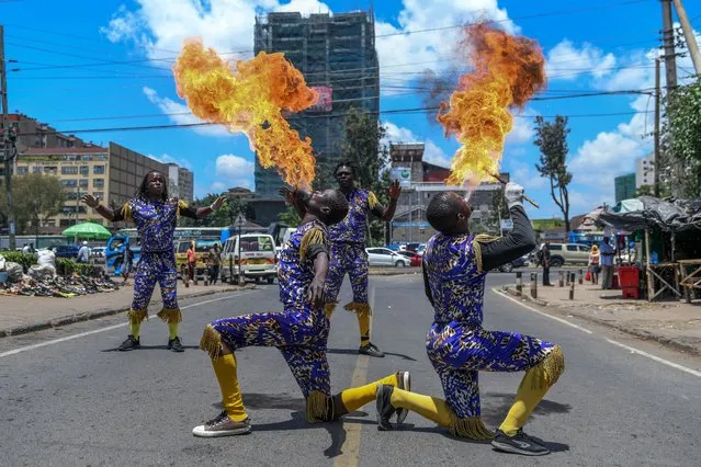 People in colorful costumes perform acrobatics for drivers waiting at red lights in Nairobi, Kenya on February 20, 2024. (Photo by Gerald Anderson/Anadolu via Getty Images)