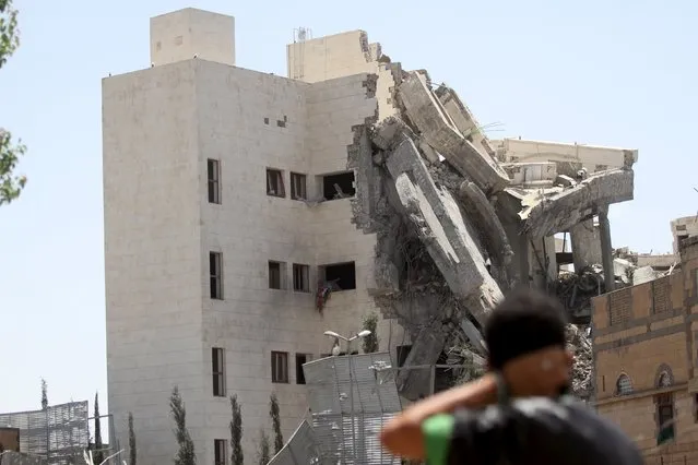 A man looks toward the residence of the Yemen's former President Ali Abdullah Saleh after airstrikes destroyed it in Sanaa May 10, 2015. (Photo by Mohamed al-Sayaghi/Reuters)