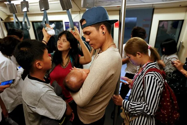 A man carries a baby while commuting on the subway in Bangkok, Thailand April 19, 2016. (Photo by Jorge Silva/Reuters)