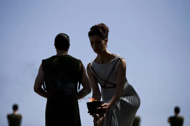 High Priestess Katerina Lehou holds a pot containing a backup flame for this summer's Rio Olympics, which she lit  earlier in a dress rehearsal, in Ancient Olympia, southern Greece,  on Wednesday, April 20, 2016. The meticulously choreographed ceremony will be repeated Thursday in the ruined birthplace of the ancient Olympics in southern Greece, in the presence of top International Olympic Committee and Rio organizing officials. That will touch off a relay that will conclude with the Rio Games opening ceremony in August. (Photo by Petros Giannakouris/AP Photo)