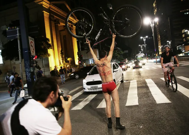 A cyclist takes part in the “World Naked Bike Ride” to defend the rights of cyclists to ride on the streets in safety, on Paulista Avenue in Sao Paulo, Brazil, March 11, 2017. The phrase on the men's back reads, “Obscene is the car traffic”. (Photo by Nacho Doce/Reuters)