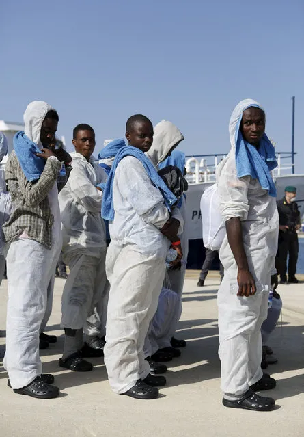 Migrants stand after disembarking from the expedition vessel Phoenix in the Sicilian harbour of Augusta, Italy June 17, 2015. REUTERS/Antonio Parrinello
