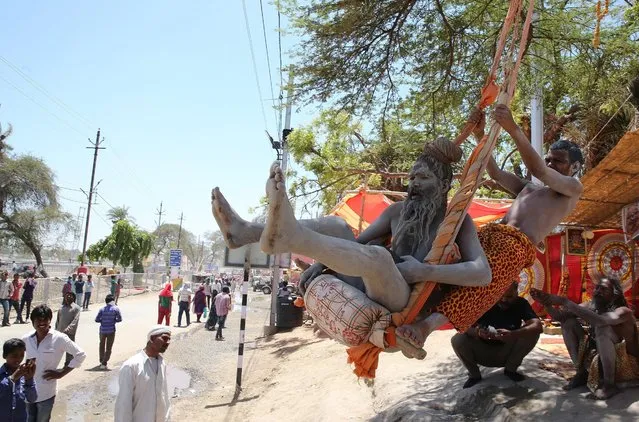 Indian Naga Sadhus (holy men) take rides on a swing during the one-month long Simhastha Kumbh Mela festival in Ujjain, some 180 km from Bhopal, India, 21 April 2016. Kumbh Mela is a mass Hindu pilgrimage which occurs every twelve years and rotates among four locations. The festival is being held from 22 April to 21 May. (Photo by Sanjeev Gupta/EPA)