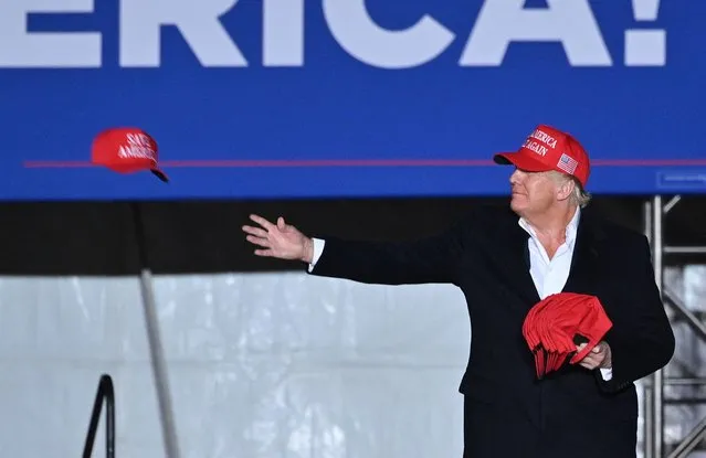 Former US President Donald Trump throws “Save America” hats to his suporters during a rally at the Canyon Moon Ranch festival grounds in Florence, Arizona, southeast of Phoenix, on January 15, 2022. Thousands of Donald Trump supporters gathered in Arizona on Saturday to hear a raft of speakers claim the 2020 US election was stolen, with the former president expected to take to the stage as the headline act. (Photo by Robyn Beck/AFP Photo)