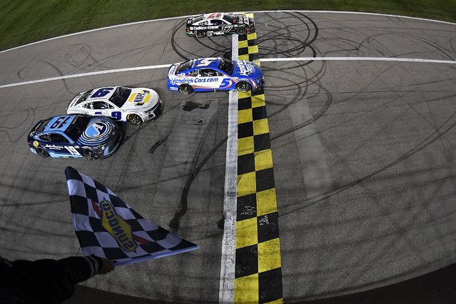 Kyle Larson, driver of the #5 HendrickCars.com Chevrolet, takes the checkered flag over Chris Buescher, driver of the #17 Castrol Edge Ford, to win the NASCAR Cup Series AdventHealth 400 at Kansas Speedway on May 05, 2024 in Kansas City, Kansas. (Photo by Logan Riely/Getty Images/AFP Photo)